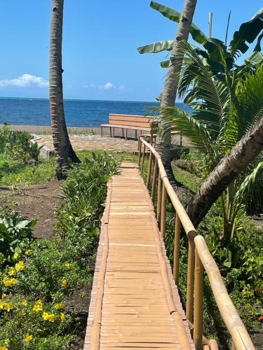 a wooden path leading to the beach with a bench at Agoho Resort in Mambajao