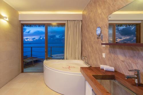 a bathroom with a tub and a view of the ocean at Cocoon Maldives - All Inclusive in Lhaviyani Atoll