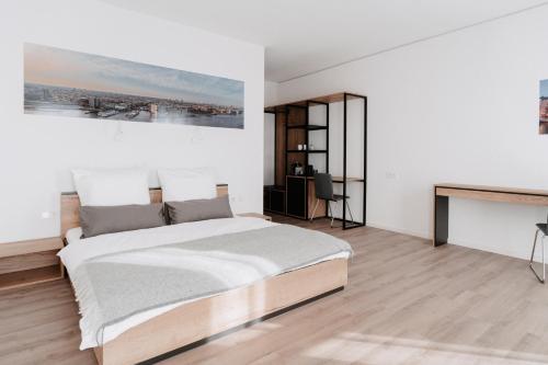 a white bedroom with a bed and a desk at STEP INN The Fair Hotel in Rosbach vor der Höhe