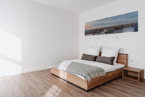 a white bedroom with a bed and a picture on the wall at STEP INN The Fair Hotel in Rosbach vor der Höhe