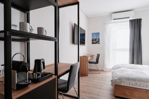 a bedroom with a desk and a bed and a table at STEP INN The Fair Hotel in Rosbach vor der Höhe