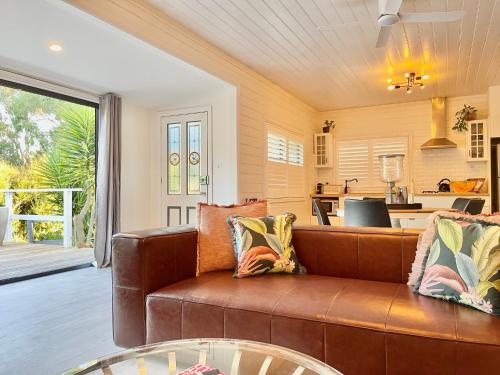 a living room with a brown couch and a kitchen at Château Rosemund - ‘Your home away from home’. in Daylesford