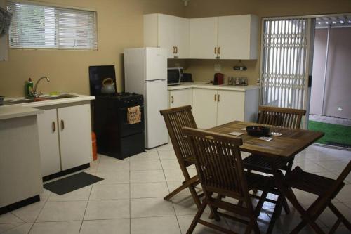 a kitchen with a table and chairs and a refrigerator at Casa en Gregg -Exquisite 2-bedroom self catering unit - 1 car parking space in East London