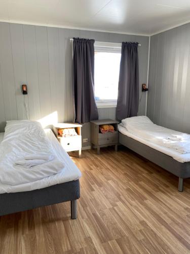 two beds in a room with a window at In the heart of the Lyngen alps, Holmen i Lyngen in Lyngseidet