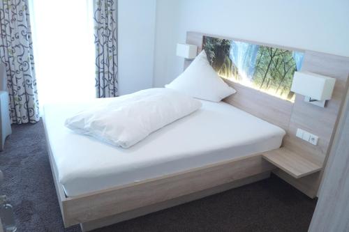 a bedroom with a white bed with a window at Gasthof Lamm in Grabenstetten