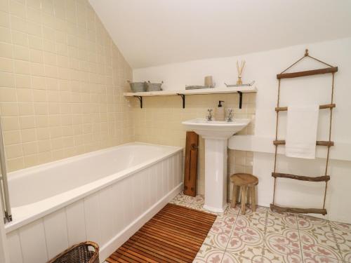 a bathroom with a tub and a sink at Hobbes Cottage in Malmesbury