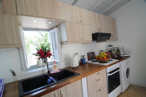 una pequeña cocina con fregadero y ventana en LOVELY QUIET HOUSE WITH GARDEN en Spétses