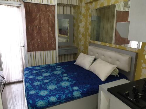 Cette petite chambre comprend un lit avec des draps et des oreillers bleus. dans l'établissement Green Pramuka Apartement By Vici, à Jakarta