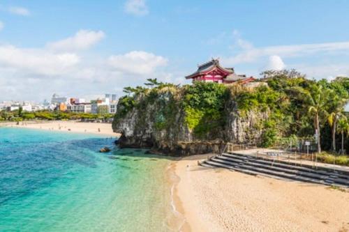 a view of a beach with a building on a cliff at Yomitan Ocean View Apartment 201 in Yomitan