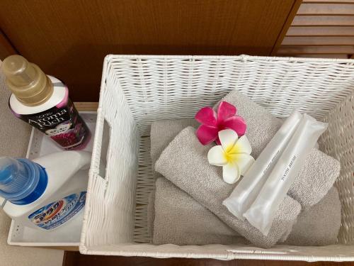 a white basket with towels and a flower on it at Yomitan Ocean View Apartment 201 in Yomitan