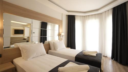 een hotelkamer met 2 bedden en een spiegel bij Alesta Seaside Residence in Fethiye