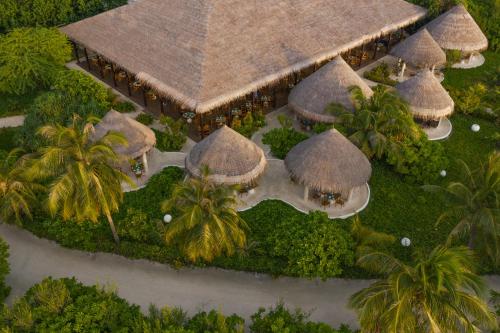 an overhead view of a resort with thatched roofs and palm trees at Cocoon Maldives - All Inclusive in Lhaviyani Atoll