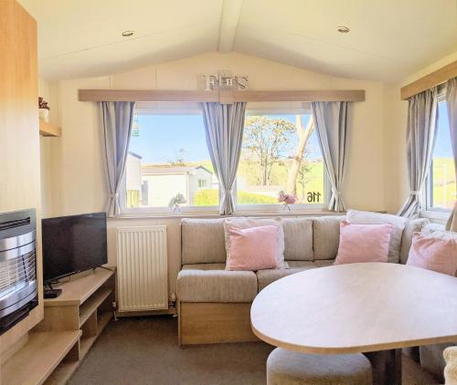 ein Wohnzimmer mit einem Sofa und einem Tisch in der Unterkunft 4 Berth Couples and Family Caravan in Beautiful Newquay Bay Resort in Newquay