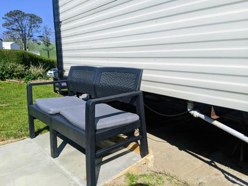 a black chair sitting in front of a garage at 4 Berth Couples and Family Caravan in Beautiful Newquay Bay Resort in Newquay