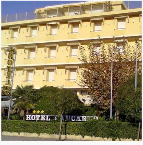 ein großes gelbes Hotel mit einem Schild davor in der Unterkunft Hotel San Carlo in Marina di Pietrasanta