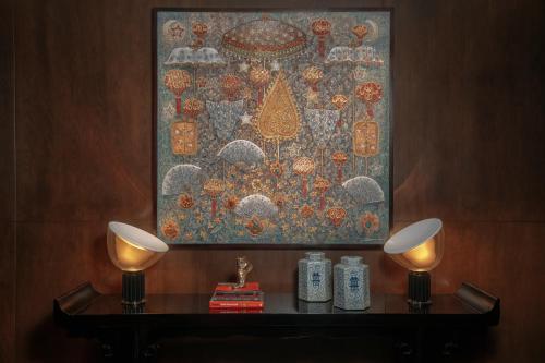 a painting on a wall with two candles on a table at Rosewood Phnom Penh in Phnom Penh