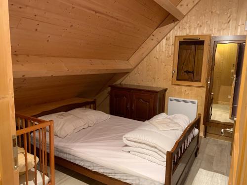 une chambre avec un lit dans une cabane en bois dans l'établissement Chalet montagnard Perce Neige avec terrasse plein sud-5 personnes, à Murat-le-Quaire