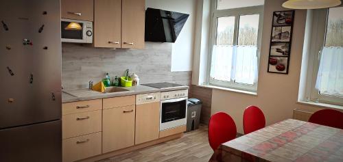 una cocina con armarios de madera y una mesa con sillas rojas. en Ferienwohnung am Birkenwäldchen, en Plauen