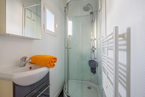 a bathroom with a glass shower and a sink at Maison au cœur de la bastide libournaise in Libourne