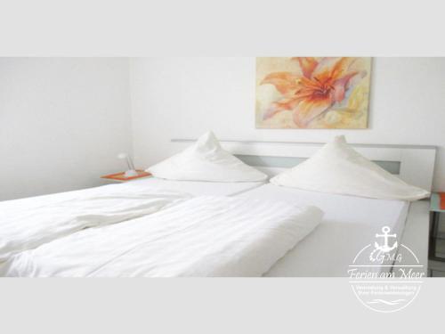 - un lit blanc avec des draps blancs et une peinture murale dans l'établissement Am Koper Sand 28 - Wg 1, à Norddeich