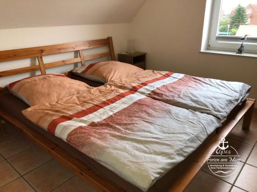 a bed with a wooden frame with a blanket on it at Atlantik-Kolk 30 in Norddeich