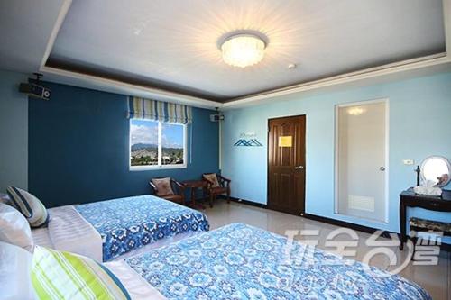 台東市的住宿－蕃茄咖啡民宿，一间卧室设有两张床和蓝色的墙壁