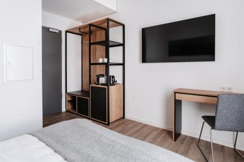 a bedroom with a bed and a desk and a television at STEP INN The Fair Hotel in Rosbach vor der Höhe