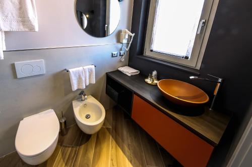 a bathroom with a sink and a toilet and a mirror at Vicolo Malavolta 7 Rooms and Suites in Pedaso
