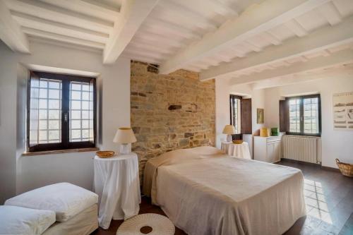 1 dormitorio con 2 camas y pared de piedra en Casale Oliva in a landscape of oaks, olive e cherry trees, en Santa Vittoria in Matenano