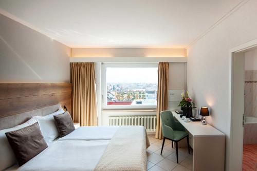 a hotel room with a bed and a desk and a window at Hotel Polo in Ascona