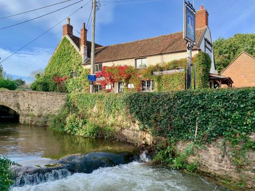 a river in front of a building and a bridge at The White Horse Inn in Washford