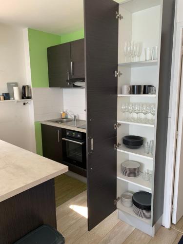 a kitchen with a black cabinet with plates and glasses at Appartement Design VIII - Port Rosmeur - Sublime vue Mer in Douarnenez