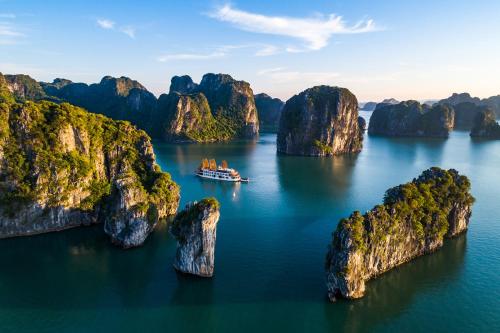 a boat in the water with many rock formations at Emperor Cruises Legacy Ha Long in Ha Long