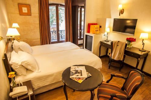 a hotel room with a bed and a table and a television at Europe Saint Severin-Paris Notre Dame in Paris
