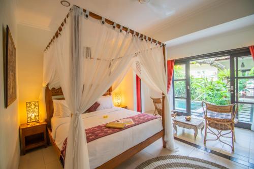 a bedroom with a canopy bed and a balcony at Kembali Lagi Guest House in Sanur
