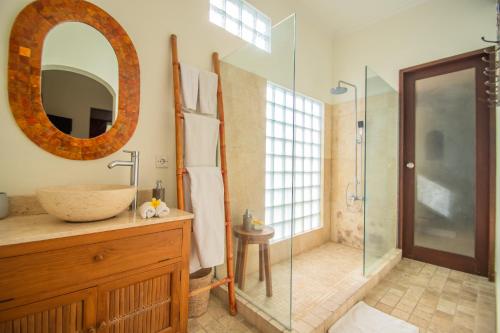 a bathroom with a sink and a glass shower at Kembali Lagi Guest House in Sanur