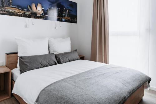 a bedroom with a bed with white sheets and a window at STEP INN The Fair Hotel in Rosbach vor der Höhe