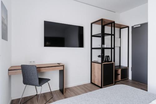 a room with a desk and a chair and a television at STEP INN The Fair Hotel in Rosbach vor der Höhe
