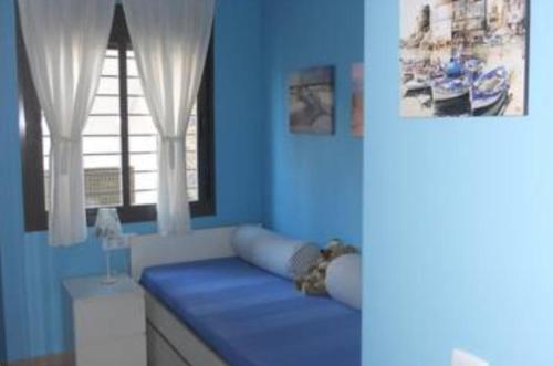 um quarto azul com uma cama e uma janela em Islantilla Bajo con Jardin na Islantilla