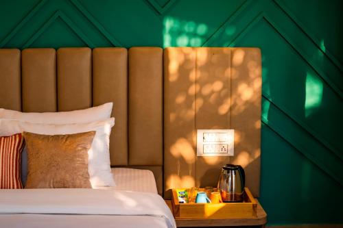 a hotel room with a bed and a night stand with a tea kettle at Zostel Plus Lonavala in Lonavala