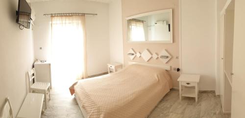 a white bedroom with a bed and a mirror at Porto Castello in Fira