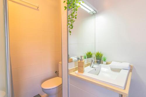 a bathroom with a sink and a toilet and a mirror at Hostel Neon Tenerife in Guaza