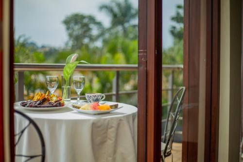a table with two plates of food and wine glasses at Humura Resorts in Kampala