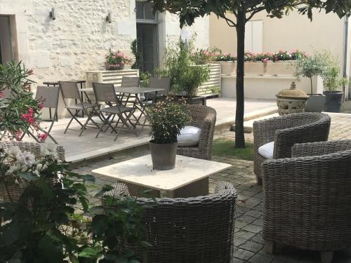 a patio with wicker chairs and a table with plants at Maison Charles Maurice in Chalais