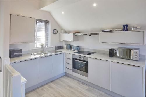 uma cozinha branca com armários brancos e um lavatório em Host & Stay - Jet Cottage @ Spa Well em Whitby
