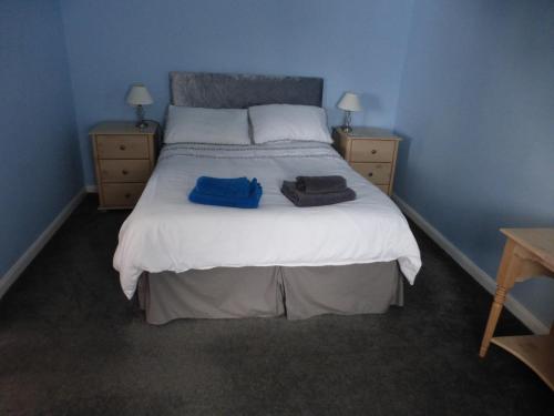 a bedroom with a bed with two blue towels on it at self-contained private apartment in Barnet
