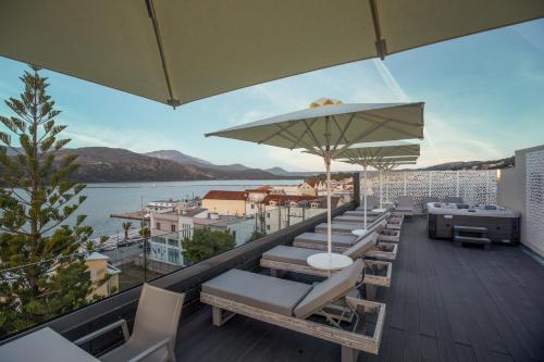 einen Balkon mit Stühlen, einem Sonnenschirm und Wasser in der Unterkunft Mouikis Hotel Kefalonia in Argostoli