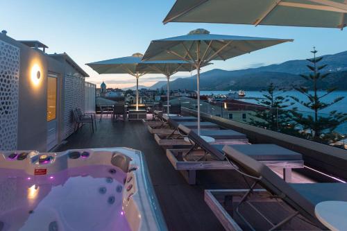 a hot tub on the roof of a hotel with chairs and umbrellas at Mouikis Hotel Kefalonia in Argostoli