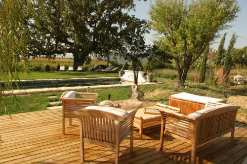 a wooden deck with chairs and a table on it at La Fontaine des Noyers in Saint-Saturnin-les-Apt