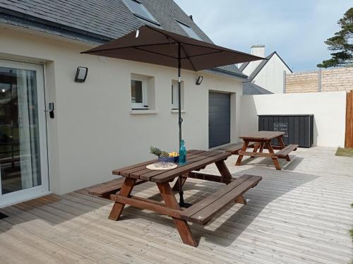 a wooden picnic table with an umbrella on a patio at Gîte L ' Escale 300 m à pied des plages in Plouarzel